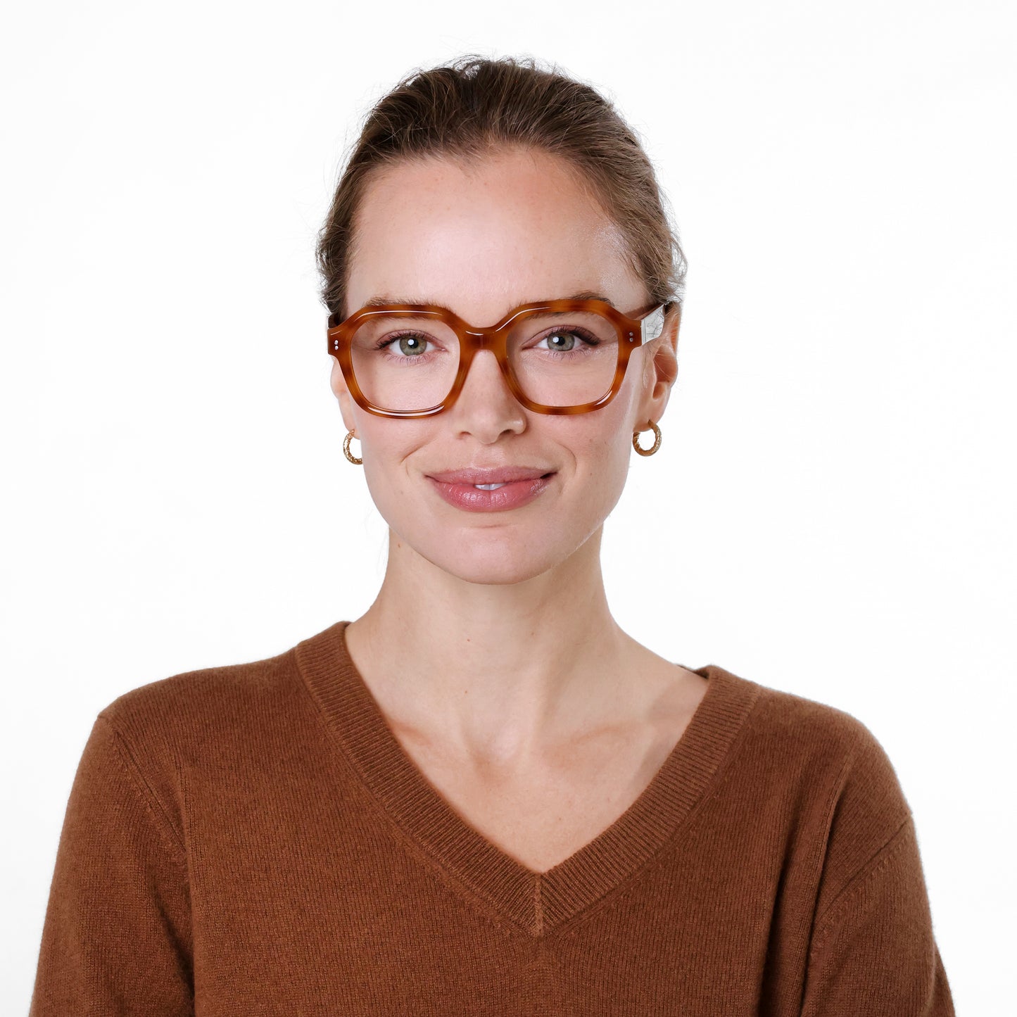 A person is wearing shiny brown tortoiseshell rectangle glasses with clear lenses.