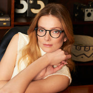 
A person is wearing round black eyeglass frames with clear lenses.