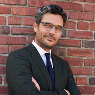 
A man wears shiny aqua round frames with clear lenses.