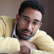 
A person is wearing round taupe frames with a clear lens tint.