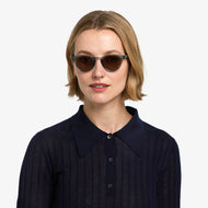 
A person is wearing round shiny aqua frames with dark tinted lenses.