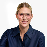 
A person is wearing gold aviator glasses with a pink tint.
