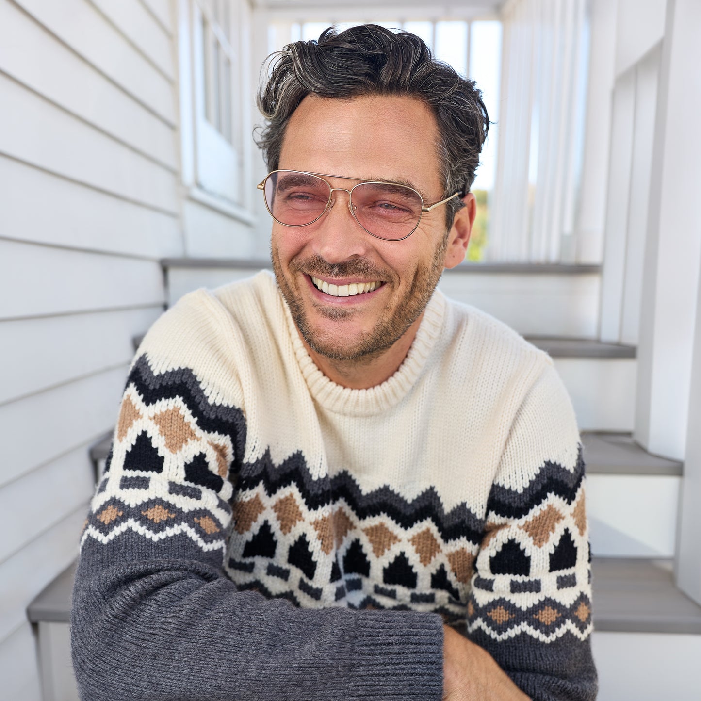 
A man wears gold aviator frames with pink tinted lenses.