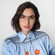
A person wears gunmetal aviator glasses with clear lenses.