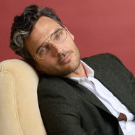 
A man wears shiny rose gold aviator frames with clear lenses.