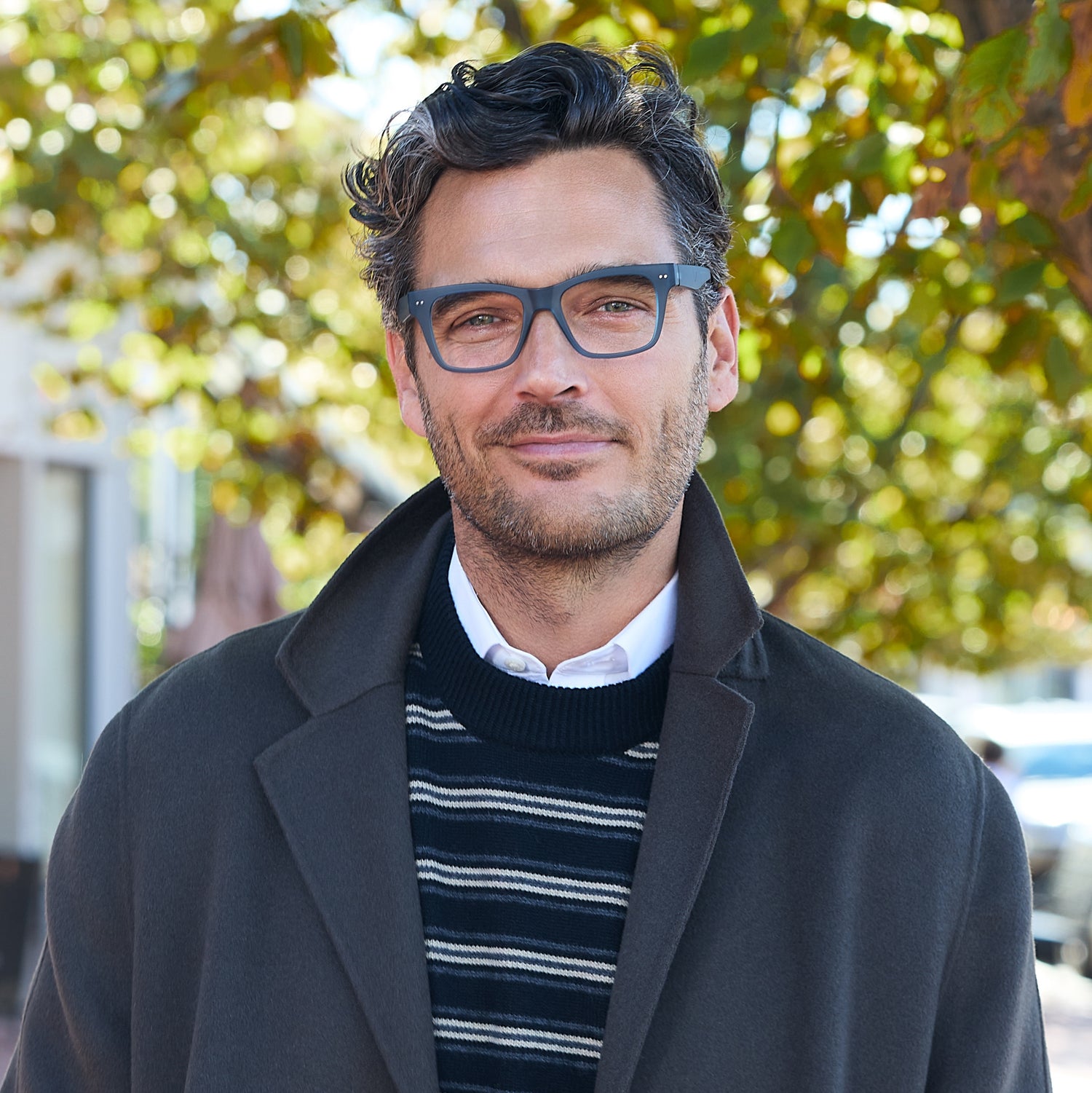 
A man wears matte lake blue square frames with clear lenses.