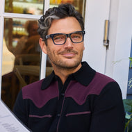
A man wears shiny navy square frames with clear lenses.