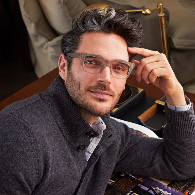 
A person wears square taupe glasses with a translucent finish and lightly tinted lenses.