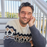 
A man wears translucent champagne rounded rectangular frames with clear lenses.