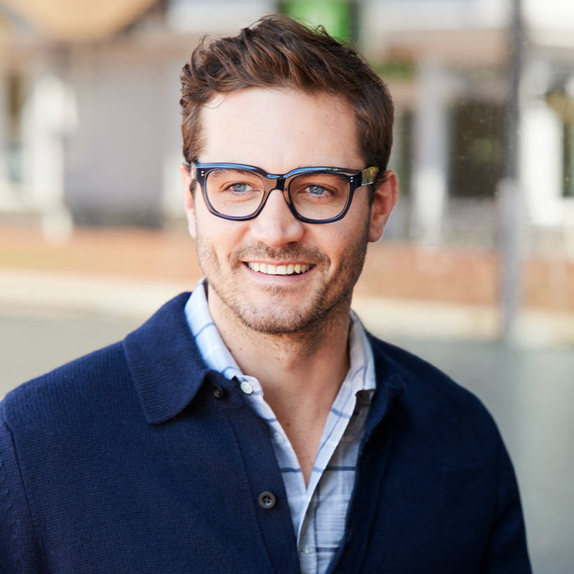 
A man wears shiny navy square frames with clear lenses.