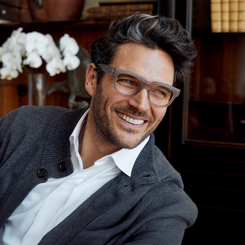 
A man wears taupe square frames with clear lenses.