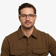 
A person is wearing square taupe glasses with a translucent matte finish and clear lenses.