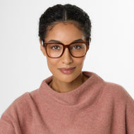 
A person wears square brown eyeglass frames with clear lenses.