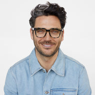 
A person wears shiny green tortoise square glasses with clear lenses.