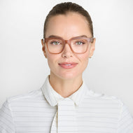 
A person is wearing square champagne coloured frames with a translucent finish and clear lenses.