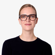 
A person is wearing square tortoise frames with a glossy finish and clear lenses.