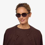 
A person is wearing shiny jade oval frames with dark tinted lenses.