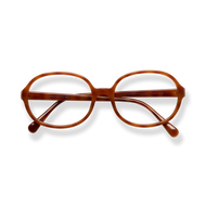 
Brown tortoiseshell oval reading glasses with slim arms on a black background.