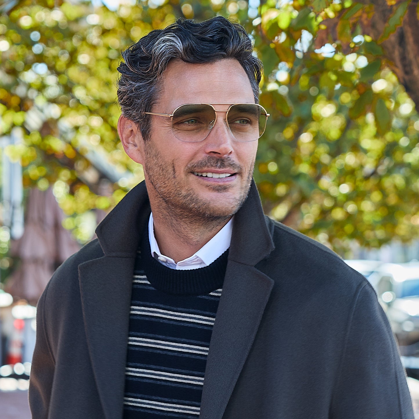 
A man wears gold square metal frames with green gradient tinted lenses.