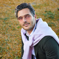 
A man wears gold metal frames with pink tinted lenses.