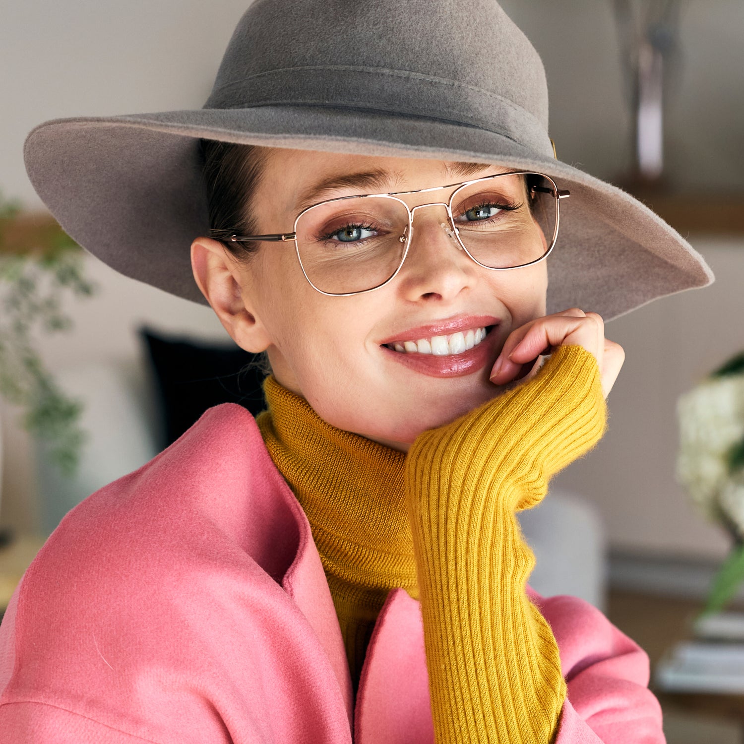 
A person in a wide-brim hat wears shiny rose gold aviator-style eyeglasses with a double bridge and clear lenses.