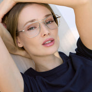 
A person in a navy top wears silver aviator-style eyeglasses with a double bridge and clear lenses.