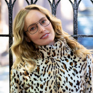 
A woman wears black metal aviator frames with clear lenses.