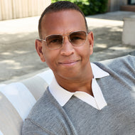 
A person in a gray knit polo wears shiny rose gold aviator-style eyeglasses with a double bridge and brown gradient tinted lenses.