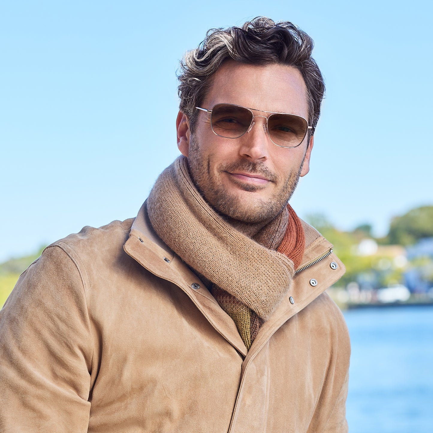 
A man wears shiny rose gold aviator-style frames with a double bridge and brown gradient tinted lenses.