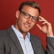 
Round navy frames with lightly tinted lenses, worn by a person.