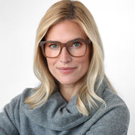 
A person is wearing square brown glasses with a translucent finish and clear lenses.