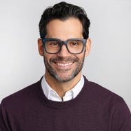 
A person is wearing square navy frames with a translucent finish and lightly tinted lenses.